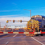 A train crosses a busy street at a railroad crossing