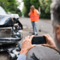 A man takes a photo after a crash, representing the need to document evidence and contact West Virginia car accident lawyers.