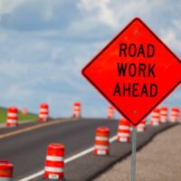 Road construction zone with orange warning sign.